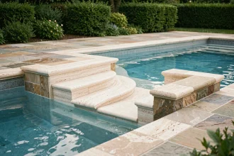 Escalier romain intégré en travertin dans une piscine enterrée avec marches courbes descendant dans l'eau turquoise